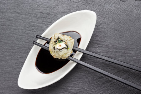 Sushi on chopsticks on a bowl with sauce. flat lay. Black background.の写真素材