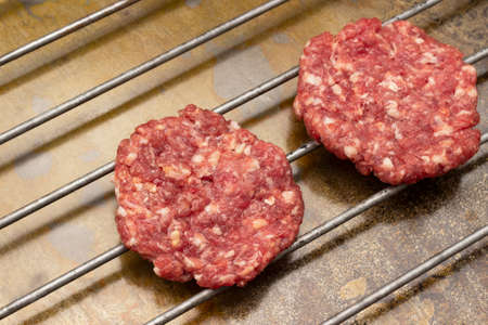 Raw beef burgers on grill. top view. Rusty metal background.の写真素材