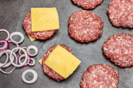 Raw beef burgers with cheese on table. flat lay. brown background.