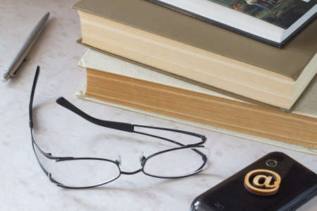 Books, glasses, pen, phone on the tableの写真素材