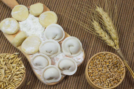 Uncooked dumplings, wheat in the box. Twig wheat on wicker napkinの写真素材
