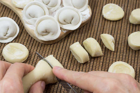 Uncooked dumplings. Hands cut the dough into piecesの写真素材