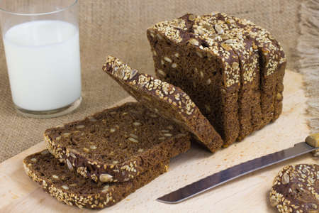 Sliced black bread, a knife and a glass of milkの写真素材