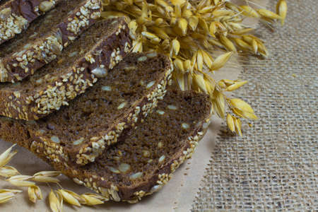 Black bread with sesame seeds and sunflower seeds, wheat ears on sackingの写真素材