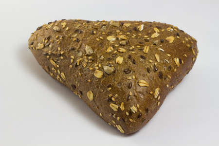 A bun in the form of a triangle sprinkled with sunflower seeds and sesame seeds. white backgroundの写真素材