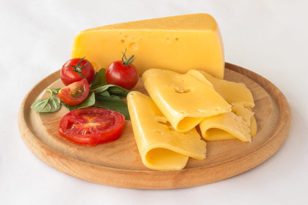 Cheese, tomato and green basil on a cutting board. white background