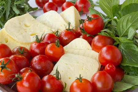 Sliced cheese, tomato and basil close upの写真素材