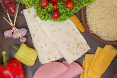 Tortilla and ingredients for her meat, tomatoes, rice, corn, peppers, tomato sauceの写真素材
