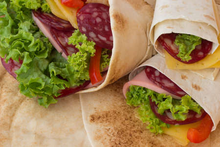 Roll tortilla with herbs, cheese and meat on a white background. close upの写真素材