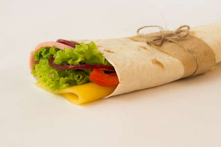 Roll tortilla with herbs, cheese and meat on a white backgroundの写真素材