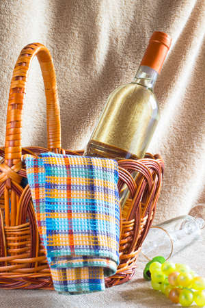 Bottle of white wine, a napkin and a bunch of grapes in a wicker basketの写真素材