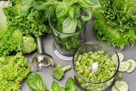 Basil and celery stalks in a blender. Lettuce leaves on the table. flat lay. gray backgroundの写真素材