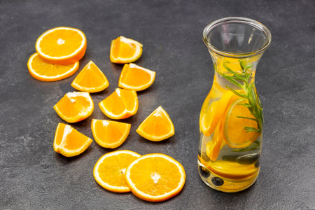 Orange slices on table. Orange infused water in glass bottle. top view. Black background.の写真素材