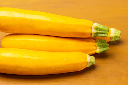 Yellow zucchini with green tails. yellow background. close upの写真素材