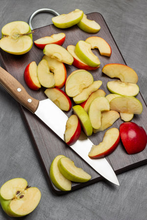 Halves a green apple. Slices of green and red apples and kitchen knife on cutting board. flat lay. gray backgroundの写真素材