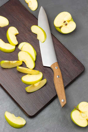 Kitchen knife and slices of green apples on cutting board. flat lay. gray background.の写真素材