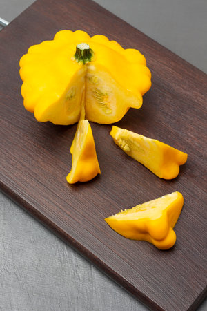 Sliced pieces of yellow patisson on cutting board. top view. gray backgroundの写真素材