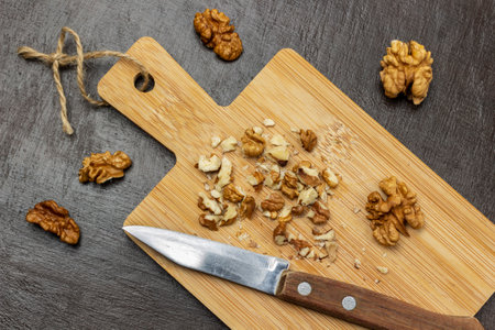 Crushed walnuts and knife on cutting board. Walnut shell and walnut kernels on the table. flat lay. brown background.の写真素材