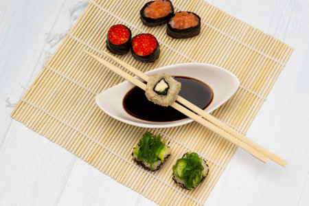 Sushi and chopsticks on bowl with soy sauce. Sushi with caviar and seaweed. flat lay. white background.の写真素材
