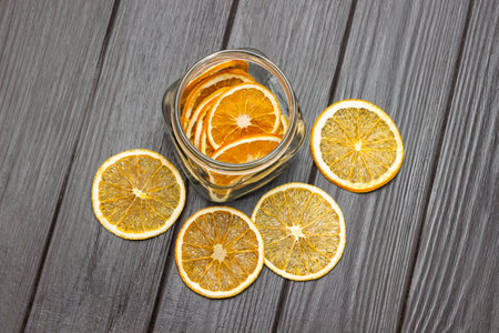Dry orange slices on the table and in a jar. flat lay. copyspace. Dark wooden background.の写真素材