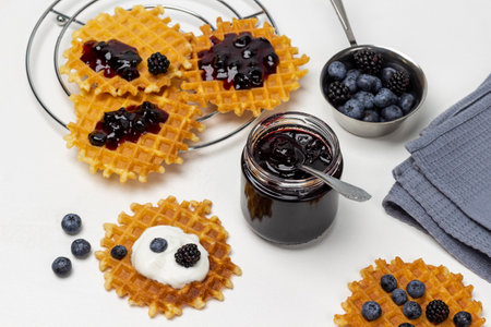 A jar of jam. Waffles with jam and berries on the table. Berries in a bowl. flat lay. white background.の写真素材
