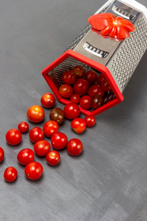 Red cherry tomatoes poured from a grater. top view. gray background.の写真素材
