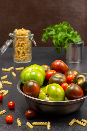 Different varieties of green and red tomatoes in a metal can. Pasta in a glass jar and parsley in a jar.の写真素材