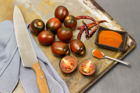 Red tomatoes, ground pepper in a bowl and pepper pods on a rusty tray. Knife and gray napkin. gray background.の写真素材