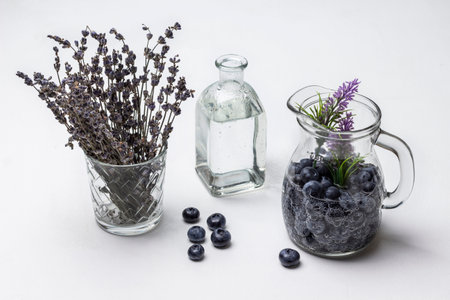 Berry refreshing drink in glass jug. water bottle. Lavender in glass. Blueberries on table. white background.の写真素材