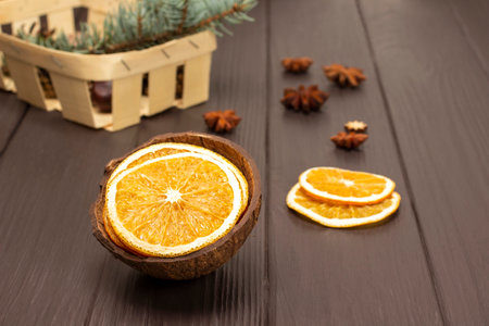 Dry slices of orange in coconut shell. Fir branch in a basket. top view. Dark wooden background.の写真素材
