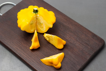 Yellow round zucchini and zucchini slices on a cutting board. top view. gray background.の写真素材