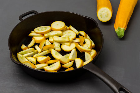 Two whole yellow zucchini. Sliced yellow zucchini in a frying pan. top view. gray background.の写真素材