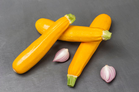 Blue onion halves and yellow zucchini. top view. gray background.の写真素材