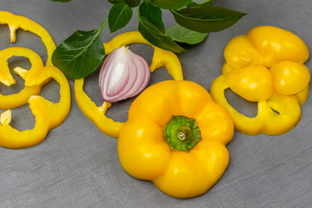 Sliced yellow pepper, blue onion wedge and greens sprig. flat lay. gray background.の写真素材