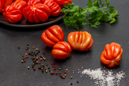 Fresh red tomatoes, parsley sprig, salt and allspice. top view. Black background.の写真素材