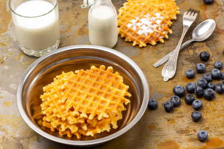 Viennese wafers in metal bowl. Waffles and berries, spoon and fork on table. Milk in glass and bottle. top view. Rusty background.の写真素材