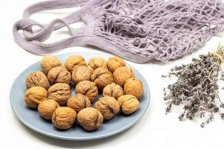 Whole walnuts on a blue plate. Bouquet of dry lavender sprigs. fabric bag. top view. white backgroundの写真素材