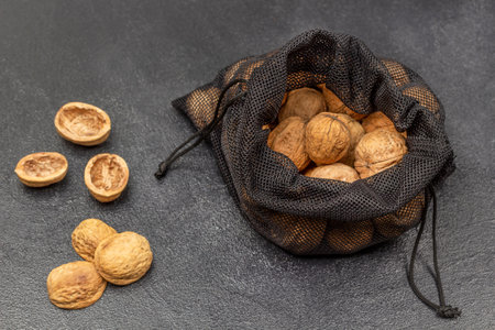 Walnuts in a black reusable bag. Nut shells on the table. top view. Black background.の写真素材
