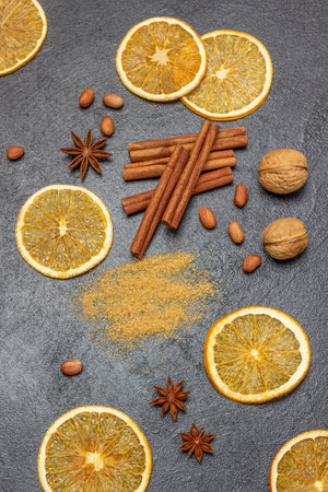 Cinnamon sticks and walnuts, orange chips and brown sugar, star anise. flat lay. black backgroundの写真素材