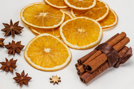 Cinnamon sticks tied in a bundle with a brown ribbon. Star anise and dry orange slices. white background.の写真素材