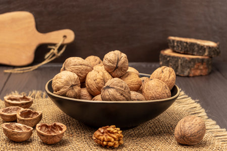 Walnuts in a bowl. Walnut shells and kernels on a burlap cloth. brown background.の写真素材