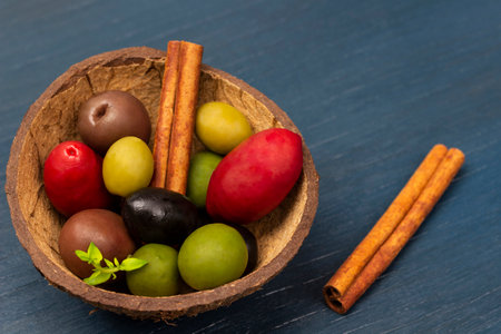 Olives of different varieties and colors in a coconut bowl. Cinnamon sticks. copyspace. top view. blue background.の写真素材