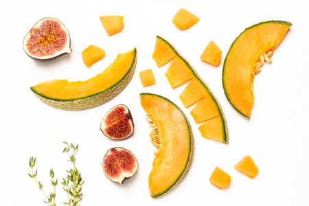 Orange melon slices and fig halves. Thyme sprigs. flat lay. white background.の写真素材
