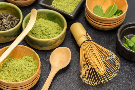 Bamboo whisk and measuring spoon. Matcha green tea powder in a bowl. close up. black backgroundの写真素材