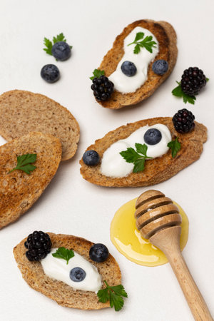 Croutons with yogurt and berries. Honey and honey stick. flat lay. white background.の写真素材