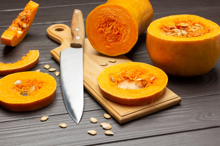 Knife and sliced pumpkin slices on cutting board. top view. dark wooden backgroundの写真素材