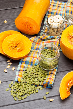 Green pumpkin seeds on napkin. Dry seeds in jar. Pumpkin slices on table. top view. dark wooden backgroundの写真素材