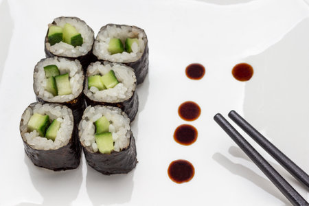 Nori maki and black chopsticks. white background. flat layの写真素材