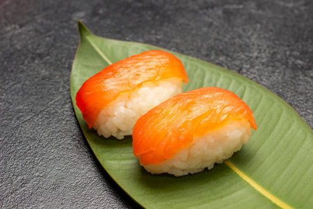 Salmon nigiri on green leaf. close up. black backgroundの写真素材