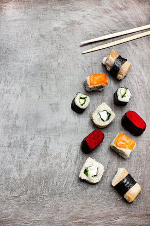 Different types of sushi and chopsticks on dark brown background. copyspace. flat layの写真素材